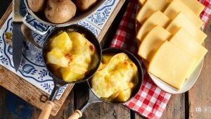 Köstlicher traditioneller Schweizer Raclettekäse auf gewürfelter gekochter oder gebackener Kartoffel.